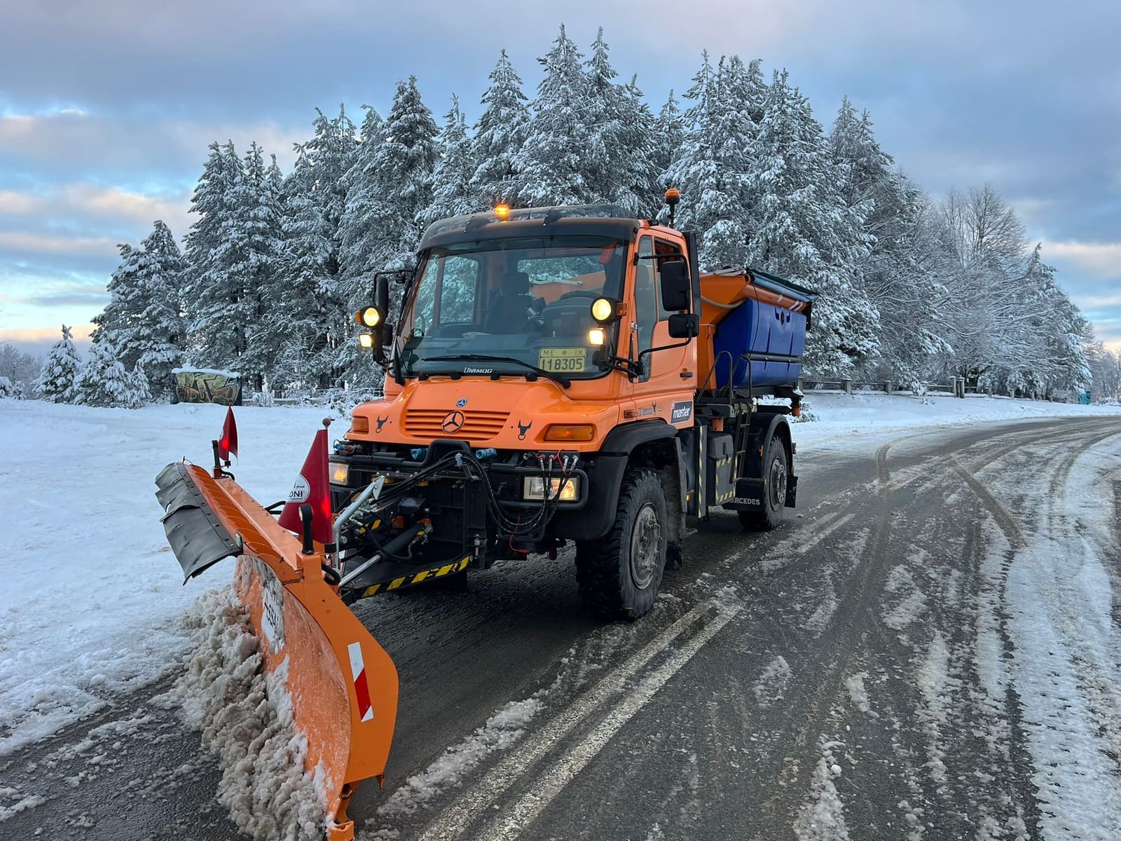 Εκχιονιστικό Unimog σε δρόμο μέσα σε χιονισμένο δάσος